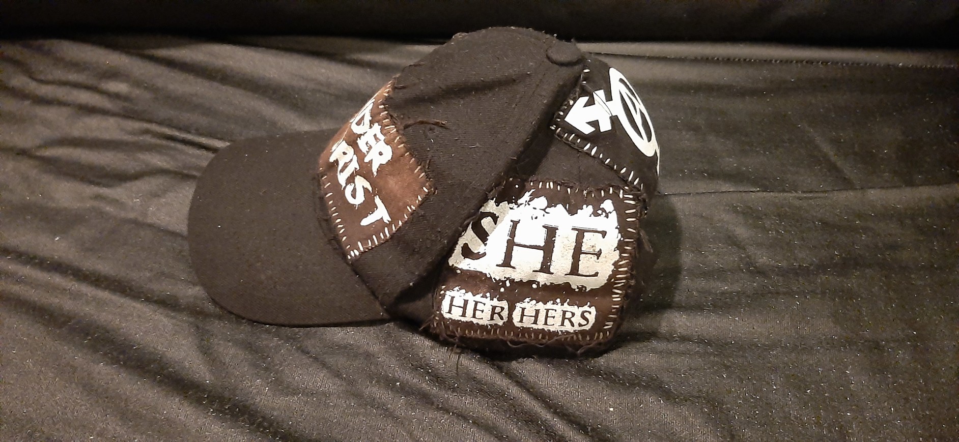 left side of my DIY'd black gender terrorist hat, which is the she/her patch'
