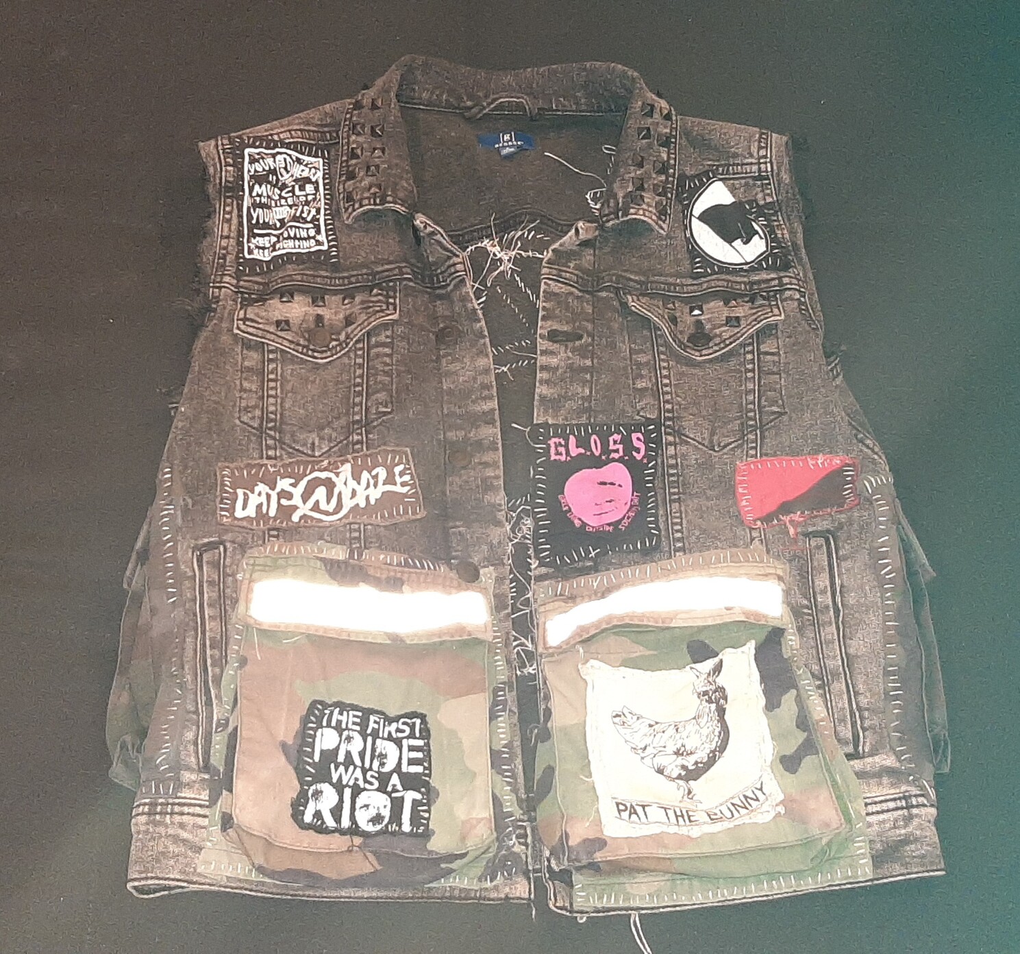 front of my grayish black denim punk vest, it has two large military cargo pockets sewn onto the front. there are various patches -- first pride was a riot, pat the bunny, gloss, days n daze, ramshackle glory, black flag, and red and black flag. the collar is studded 